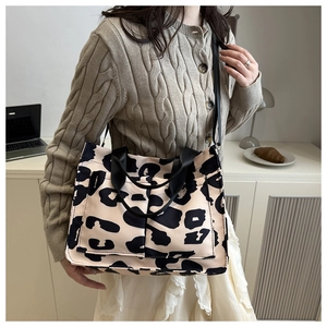 Dettaglio della borsa tote in tela leopardata con tasche frontali e tracolle nere
