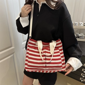 Red and white striped canvas tote bag with shoulder strap and multiple pockets shown on model
