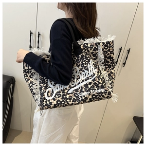 Leopard print canvas tote bag with white frayed fringe edges worn by a model