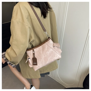 Side view of a light pink textured leather hobo bag with brown adjustable shoulder strap