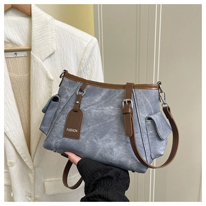 Detail of blue denim fabric texture and brown leather strap on a stylish shoulder bag