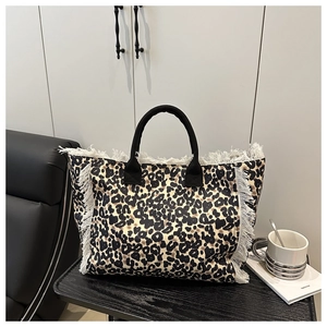 Detail of leopard print tote bag featuring white fringe edges and black sturdy handles