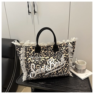 Detailed close-up of leopard print tote bag with white fringe and black handles