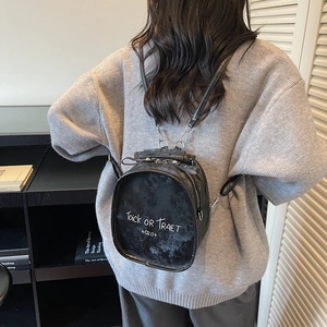 Minimalist black matte mini backpack with white graffiti lettering worn by a model
