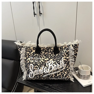 Detail of leopard print tote bag with white fringe trim and black woven handles