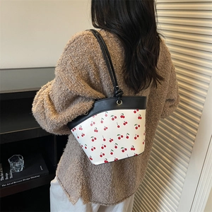 Chic white leather bucket bag with red cherry prints and slim black shoulder straps