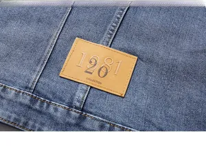 Macro view of leather patch with embossed branding on washed blue denim jacket detail