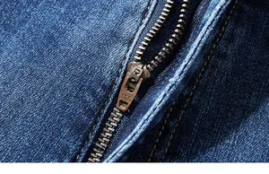 Macro shot of high-quality YKK metal zipper and durable blue denim fabric on men's jeans