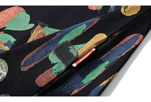 Gros plan du tissu d'un t-shirt noir ample avec coups de pinceau colorés et étiquette mode