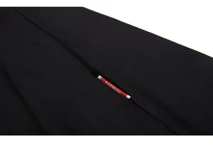 Close-up of black knit fabric with a red FASHION label on a loose cotton t-shirt