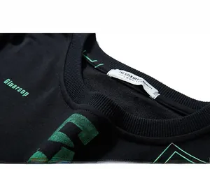 Close-up of ribbed crew neck and green letter print on a black oversized sweatshirt