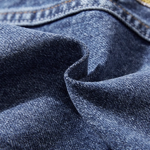 Gros plan sur un denim bleu de qualité avec délavage vintage et coutures orange