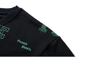 Detail of ribbed crew neck and green letter embroidery on black long sleeve sweatshirt