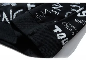 Close-up of ribbed cuffs and white street graffiti print on black oversized hoodie