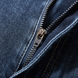 Close-up of deep blue denim jeans featuring a brass YKK zipper and classic yellow stitching