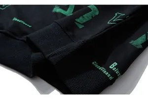 Close-up of ribbed cuff on black sweatshirt featuring green textured graphic print