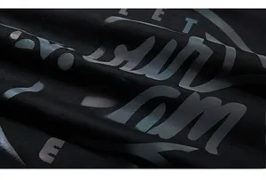 Macro shot of loose-fit black hoodie featuring reflective artistic letter prints