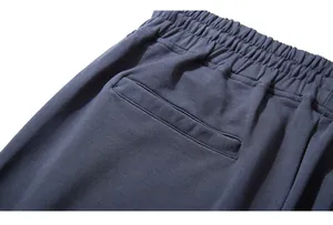 Detail of dark grey-blue sweatpants featuring elastic waistband and back welt pocket