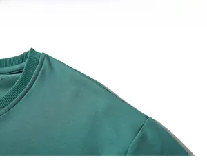 Nahaufnahme des gerippten Rundhalsausschnitts und der Schulternähte am grünen Sweatshirt