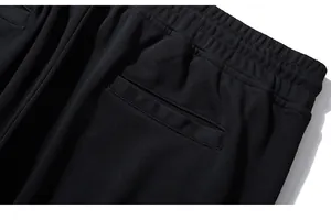 Detail of black jogger pants featuring an elastic waistband and rear welt pocket