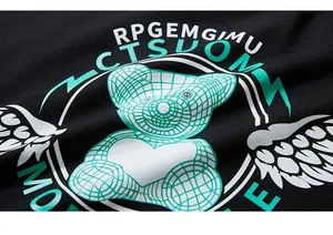 Detail of green grid teddy bear print with white heart on black cotton long sleeve tee