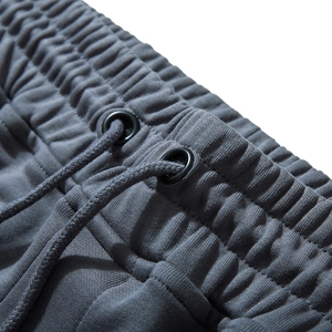 Close-up of men's gray jogger pants featuring drawstring waist and ribbed cotton texture