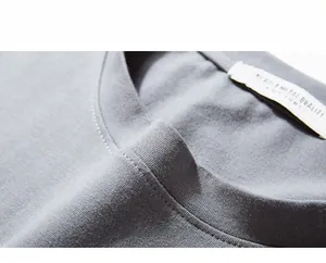 Macro detail of the reinforced crew neck stitching and label on gray cotton long sleeve tee