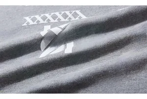 Detailed macro view of the XXXXXXL logo and green graphic print on grey cotton t-shirt