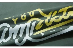 Macro detail of dark green cotton fabric with yellow and white 3D textured letter print