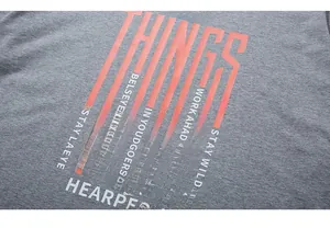 Détail d'un t-shirt gris en coton avec imprimé géométrique orange et texte MALE THINGS