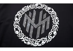 Détail d'un t-shirt noir avec un large motif géométrique en strass et nœud celtique