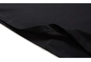 Détail de l'ourlet à double couture sur un t-shirt noir en coton à la texture fine