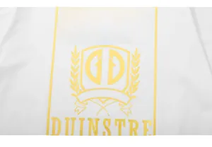 Detail of yellow graphic print with DIRDEL shield logo on a white cotton T-shirt fabric