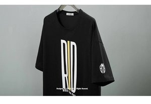 Détail de l'imprimé graphique blanc et jaune de haute qualité sur un t-shirt noir oversize