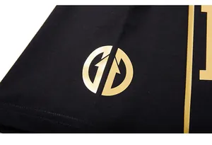 Close-up of golden foil logo printed on black knit fabric of oversized T-shirt sleeve