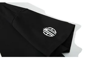Gros plan sur la manche d'un t-shirt noir oversize avec un logo imprimé géométrique blanc