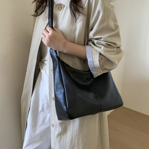 Minimalist black faux leather large hobo shoulder bag styled with an elegant beige coat