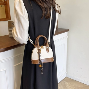 Retro cream and brown shell bag with crossbody strap shown in a cafe setting