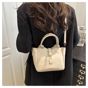 Detail of cream white faux leather bucket bag with gold clasp and FASHION lettering