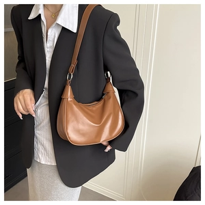 Detailed view of caramel hobo bag featuring polished faux leather and silver metal rings