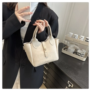 Détails du sac seau beige minimaliste avec texture rétro et finitions en métal doré