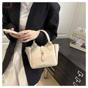 Close-up of cream bucket bag featuring pebble leather texture and gold twist lock detail