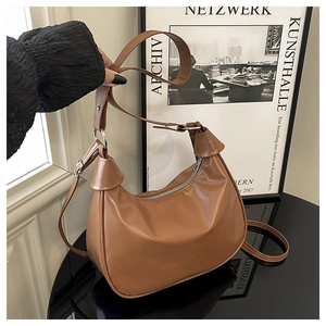 Detail of a brown leather hobo bag with adjustable strap and silver metal hardware accents