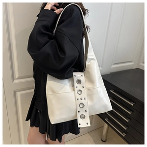 Détail d'un sac cabas blanc en similicuir brillant avec œillets et rivets argentés