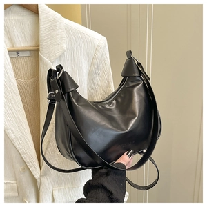 Detail of a minimalist black half-moon hobo bag with a silver zipper and smooth leather texture