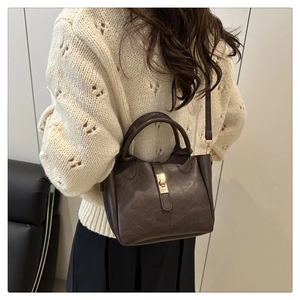 Detail of vintage dark brown bucket bag with gold twist lock and fine leather texture