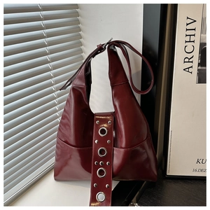 Détail du sac hobo bordeaux montrant le similicuir brillant et les oeillets argentés