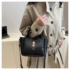 Detail of black bucket bag with lychee grain texture and golden metal lock buckle