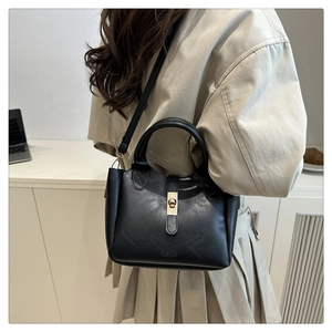 Close-up of black leather bucket bag with gold hardware lock and shoulder strap