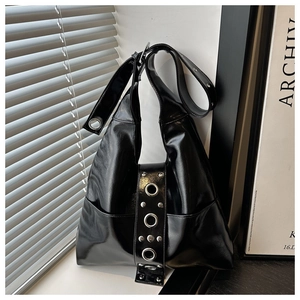 Détail du sac en cuir brillant noir avec œillets argentés et rivets style punk